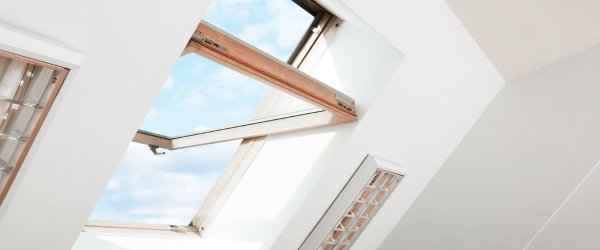 Open skylight roof window on slanted ceiling in attic room, low